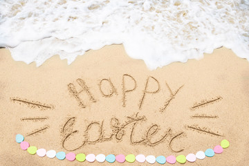 Happy easter lettering background with eggs on the sandy beach