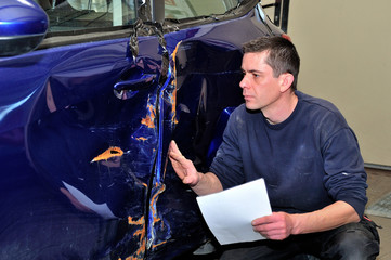 Insurance expert working at damaged car.