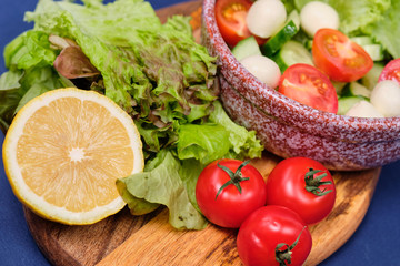 Obraz na płótnie Canvas fresh vegetables and a bowl of salad with mozzarella on a blue background. Caprese salad . Lettuce, cherry tomatoes, mozzarella, 