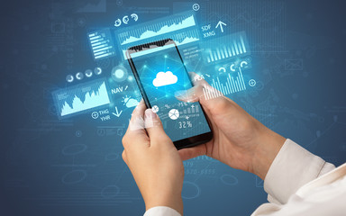 Female hand using smartphone with financial tracking concept illustrated by graphs and symbols
