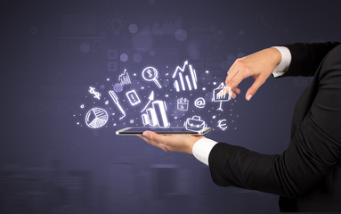 Elegant hand holding tablet with chalk drawn social media symbols above
