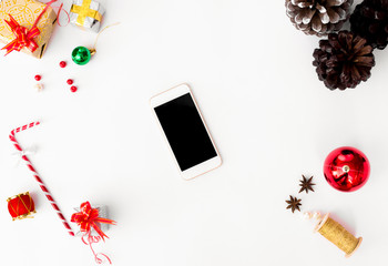 mobile smart phone mock up for christmas time. cones and colorful decorations on white background. flat lay top view.