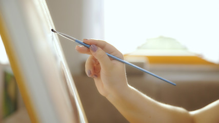 Artist hand while painting on canvas close-up