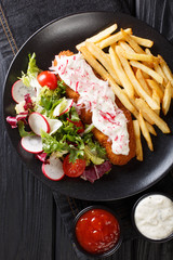 pollock in breadcrumbs garnished with French fries and fresh salad closeup. Vertical top view