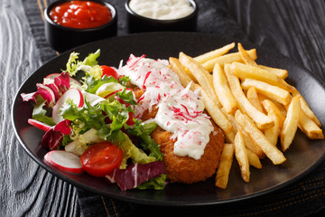 Served fried pollock in breading with french fries and fresh salad close-up on a plate and sauces. Horizontal