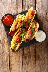 Crispy corn tacos with seafood fresh vegetables and sauces close-up. Vertical top view