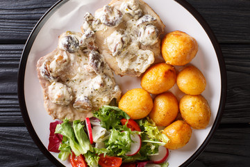 Portion of pork steak in a creamy mushroom sauce with a garnish of new potatoes and vegetable salad...
