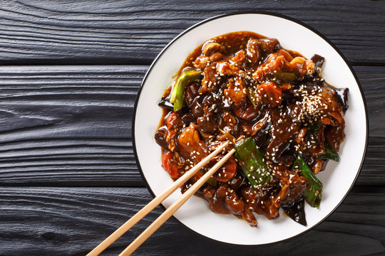 Chinese delicious stir fry pork with mun mushrooms and vegetables close-up on a plate. Horizontal top view