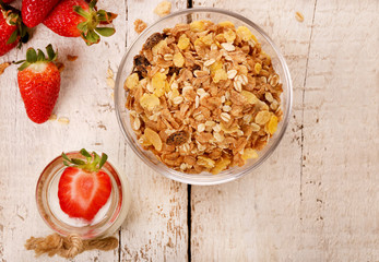 Jar with delicious yogurt and strawberry and granola muesli, over a white on wooden table