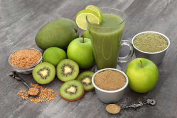 Healthy fruit juice smoothie drink with matcha and hemp powders, flax seed, with fresh fruit on rustic wood background. High in omega 3, antioxidants, vitamins and dietary fibre.