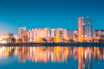 Fototapeta na wymiar Urban Residential Area Overlooks To City Lake Or River And Park In Evening Illumination, Reflecting In Water Surface. Spring In Gomel Belarus. City Residential Architecture