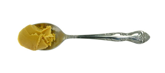 Peanut butter in a metal spoon isolated on white. 