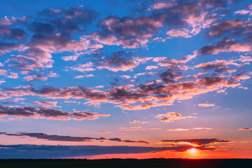 Naklejka na ściany i meble Sunset Sunrise Over Field Or Meadow. Bright Dramatic Sky And Dark Ground. Countryside Landscape Under Scenic Colorful Sky At Sunset Dawn Sunrise. Skyline