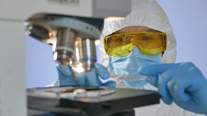 Close-up shot of a scientist looking at a glass slide with bacteria preparing for examining under...