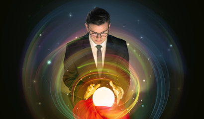 Young handsome man looking to the future of the universe in a crystal ball
