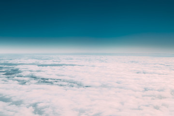 Fototapeta na wymiar Beautiful Aerial View Of Sunny Clear Sky Over White Fluffy Clouds From Height Flight Of Plane. Bright White And Blue Colors Of Sunny Sky