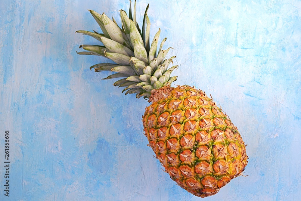 Wall mural Ripe and juicy whole pineapple on a light blue concrete background. Tropical fruit. Summer concept. Top view, copy space.