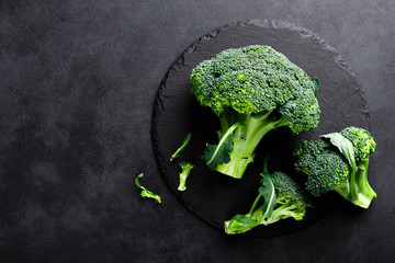 Fresh broccoli florets on black background, top view - obrazy, fototapety, plakaty