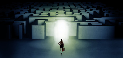 Lost woman standing at the dark labyrinth with illuminated door
