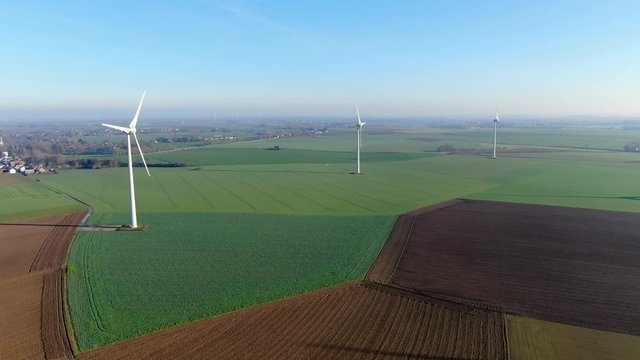 Aerial view of wind turbines and agricultural fields on a beautiful blue winter day - Energy Production with clean and Renewable Energy - aerial shot, analog image style