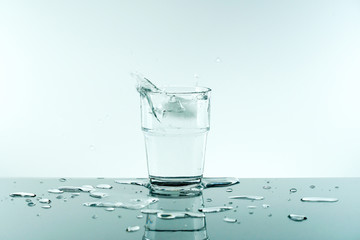 Glass of pure fresh water with ice cube.Reflection of crystal glass from the table on white background. Concept of Nature, Healthy Lifestyle. Healthcare And Beauty, freshness.