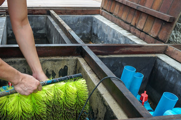 Man cleaning fish Pond Filter System for healthy fish keeping,providing a means to remove harmful substances and improve overall water quality.