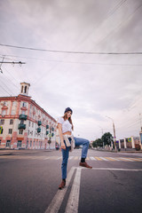 Girl posing in the middle of the roadway. Girl in stylish clothes and hat.