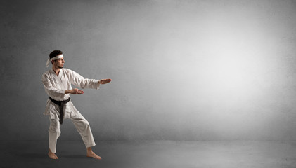 Small karate man fighting in an empty grey copy space