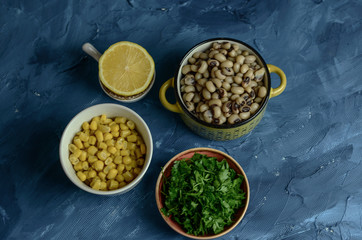 Dry cowpea salad ingredients; cowpea, lemon, parsley on blue background. Vegetarian food concept