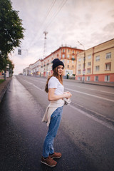 Girl posing in the middle of the roadway. Girl in stylish clothes and hat.
