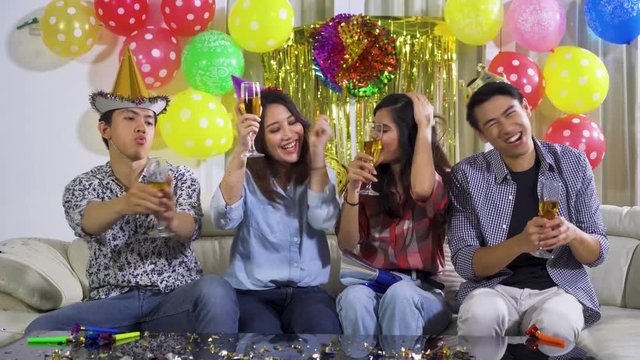 Group of cheerful young people celebrating their friend birthday while drinking champagne and toasting on the party at home. Shot in 4k resolution