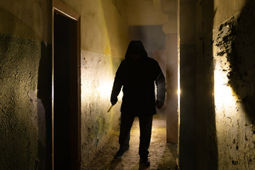 Creepy silhouette with knife  in the dark abandoned building. Horror about maniac concept