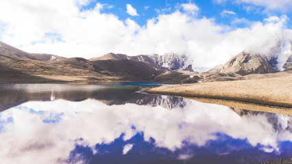 Landscape of vast sky mountain and lake with reflection of cloud in clean greenish water in nature