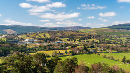 Irish countryside scene on a spring day as seen from above with agricultural land parcels, forests, houses and industrial buildings. View from the top of the Scalp, Barnaslingan Hill, Ireland.