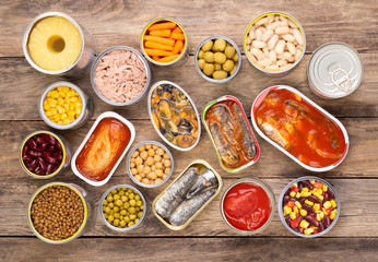 Canned food on wooden background, top view