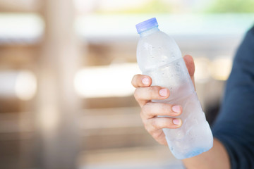 close up young man hand holding cool fresh drinking water bottle from a plastic.