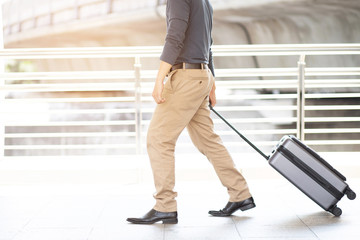businessman walking outside public transport building with luggage in rush hour. Business traveler pulling suitcase in modern airport terminal. baggage business Trip.  Copy space