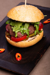 Juicy burger with veal tartar on a wooden scorched board