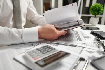 Fototapeta premium Businessman working at office and calculating finance, reads and writes reports. Business financial accounting concept.