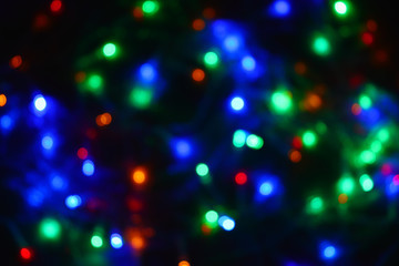 Naklejka premium Colored lights (garland) in the dark. Bokeh effect Festive illumination.