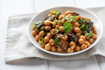 Cooked chickpeas with grilled eggplant and parsley on a plate.
