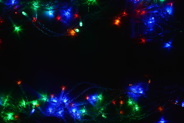 Fototapeta na wymiar Colored lights (garland) in the dark. Bokeh effect Festive illumination.