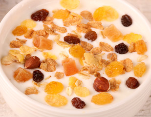 Bowl of yogurt with strawberries and granola muesli, over a white wood background.