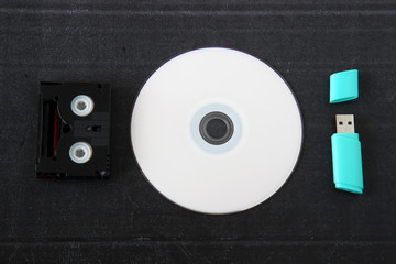 cd or dvd, flash drive, mini dv cassette on black background