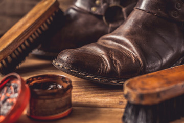 Old vintage leather boots with shoe brush on wooden background