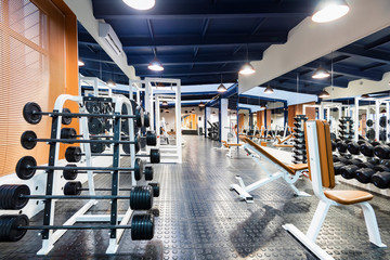 Equipment in modern gym interior. Barbells and weights