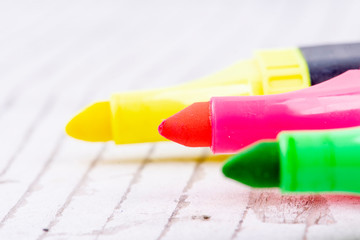 three colorful highlighters on white rustic wood