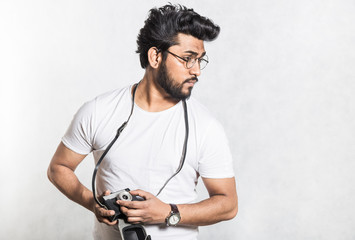 Portrait of a handsome young stylish man with beard taking photo on a vintage camera.