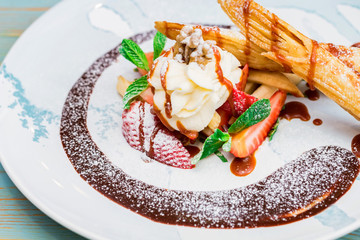 Close up delicious dessert with waffle rolls, ice cream and strawberries