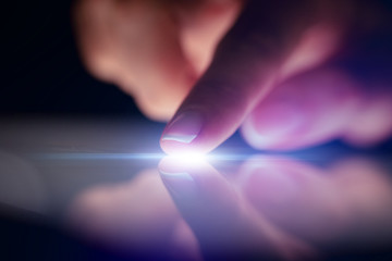 Finger touching tablet with dark background with copyspace
